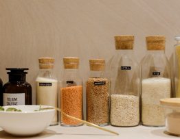 A variety of grains and pasta in labeled glass bottles displayed on a kitchen counter.
